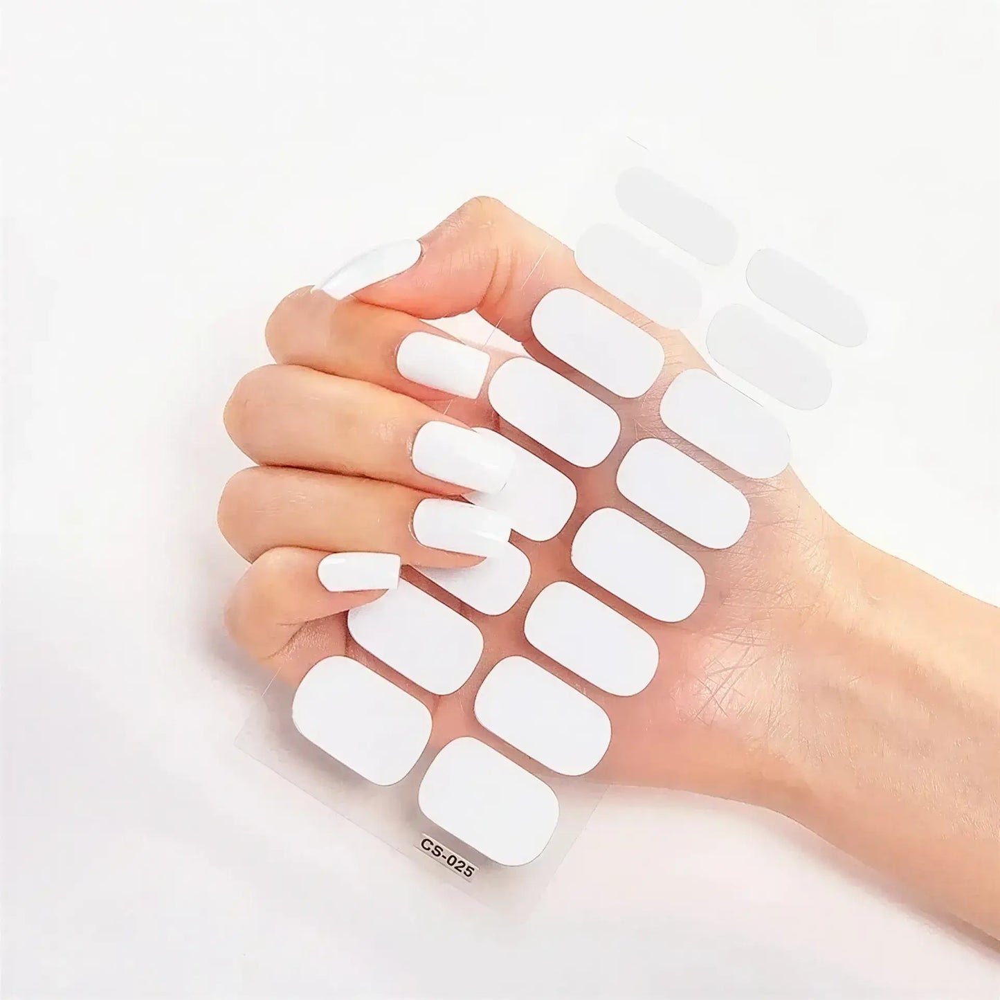 Currant nail wraps on a clear backing sheet, with a hand displaying white press-on nails.