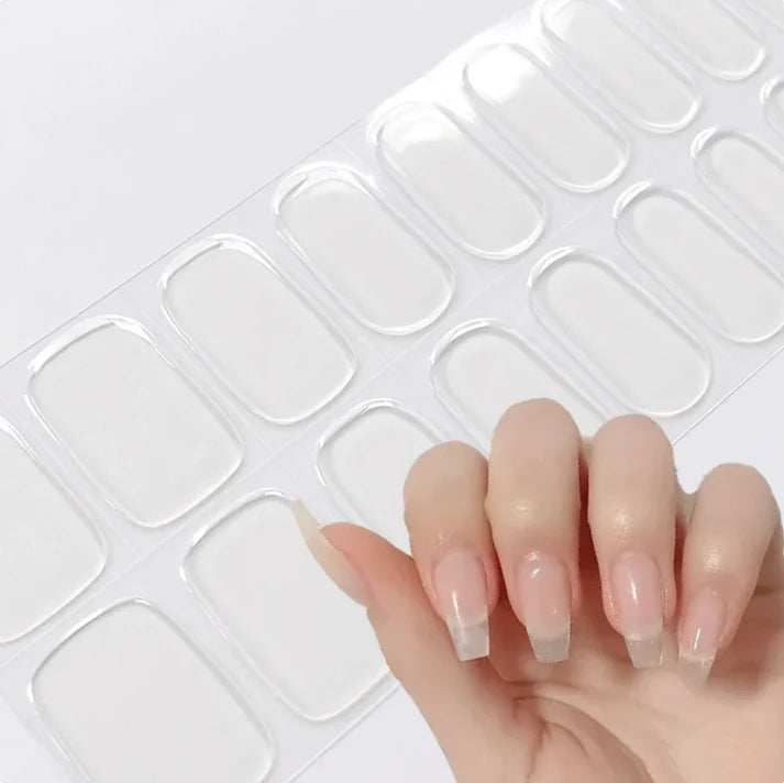 Transparent nail tips displayed on a sheet, with a hand showing manicured nails featuring a nude and clear design.
