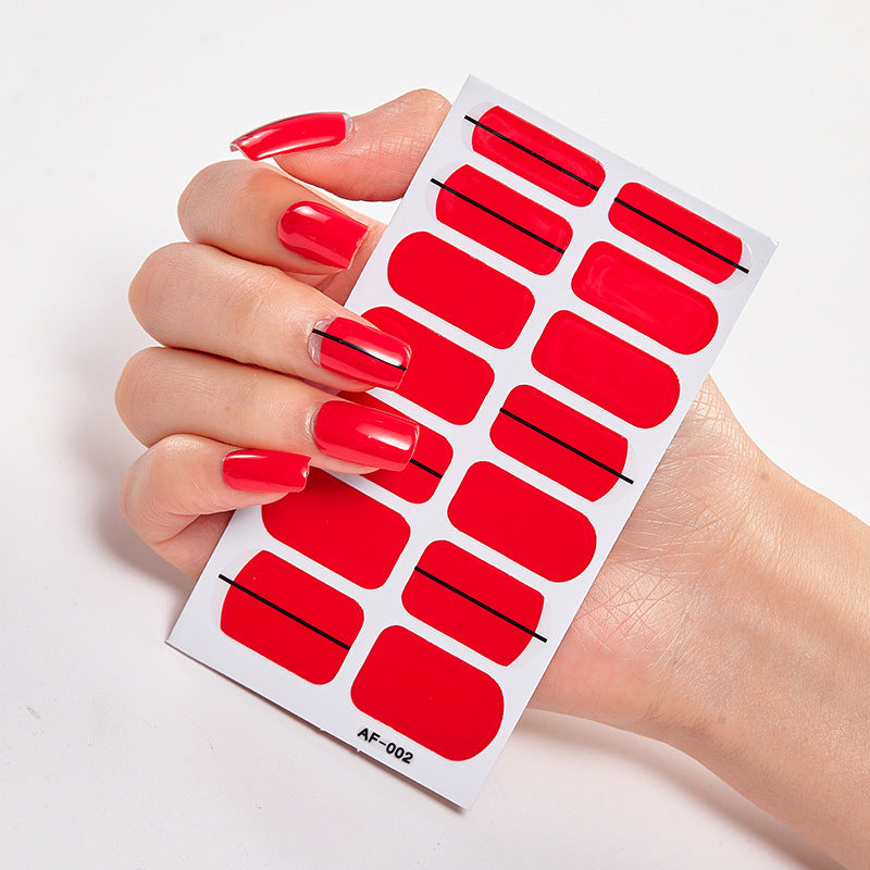 Red nail stickers held by a hand with long, manicured red nails, featuring various shapes and sizes on a white backing.