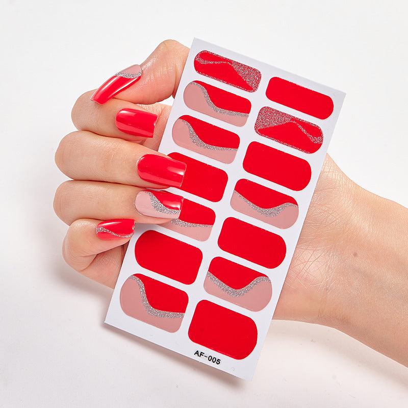 Red nail wraps with glitter accents held by a hand with long, manicured nails.