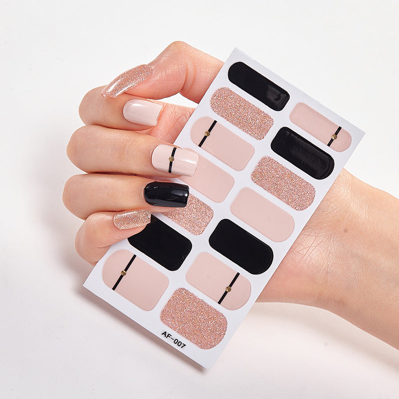 Hand holding a nail art sticker sheet featuring various shades of nude, black, and glitter designs.