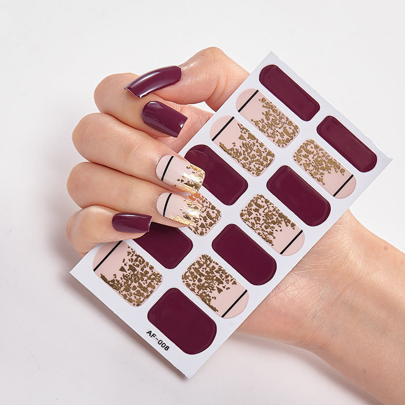 Every Shade of You nail art set featuring burgundy and gold designs on a hand with long nails.