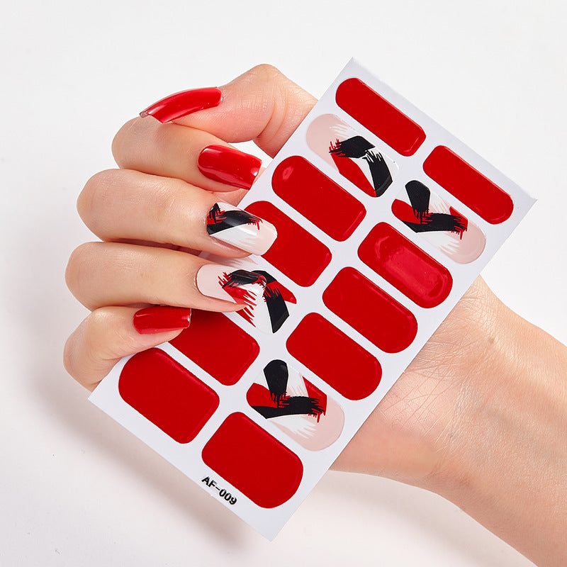 Red nail wraps featuring black abstract designs held in a hand with long red nails.