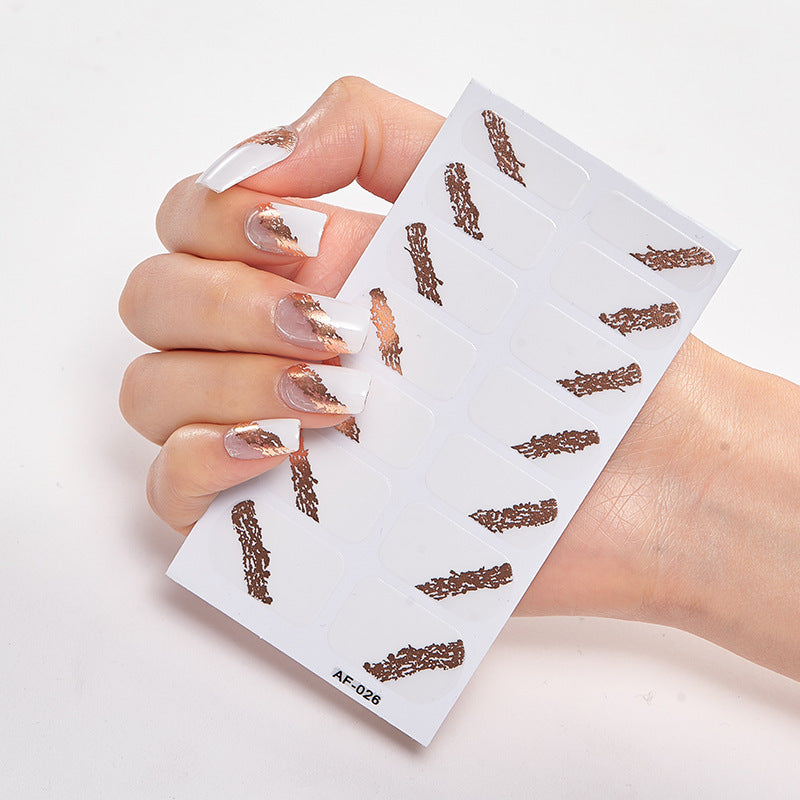 Nail art design featuring a hand holding a sheet of nail stickers with brown abstract patterns on a white background.