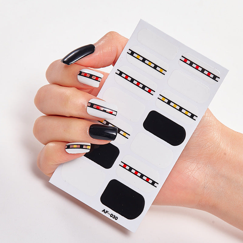 Nail art stickers featuring black, white, and colorful striped designs on a hand with manicured nails.