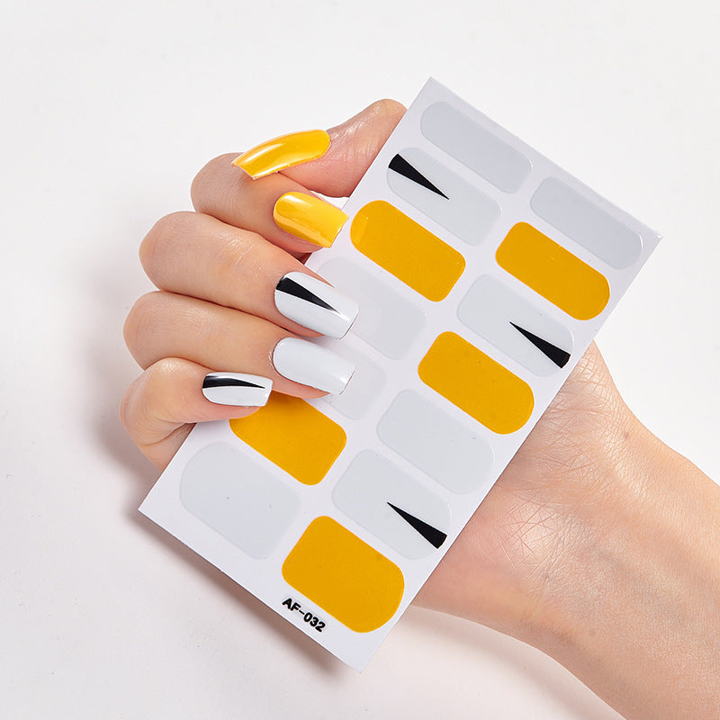Every Shade of You nail art set featuring yellow, white, and black designs on a hand holding nail stickers.