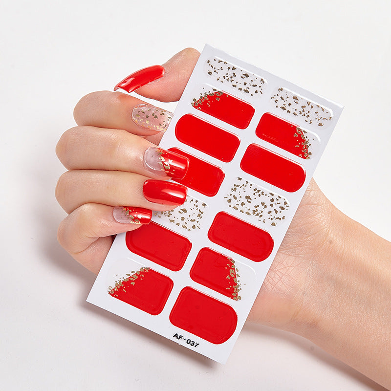 Red nail wraps with gold glitter accents held in a hand with manicured nails, showcasing various designs.