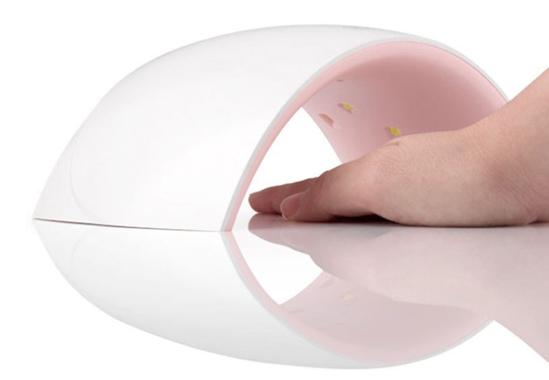 UV LED lamp with a curved white exterior and pink interior, displaying a hand underneath for scale.