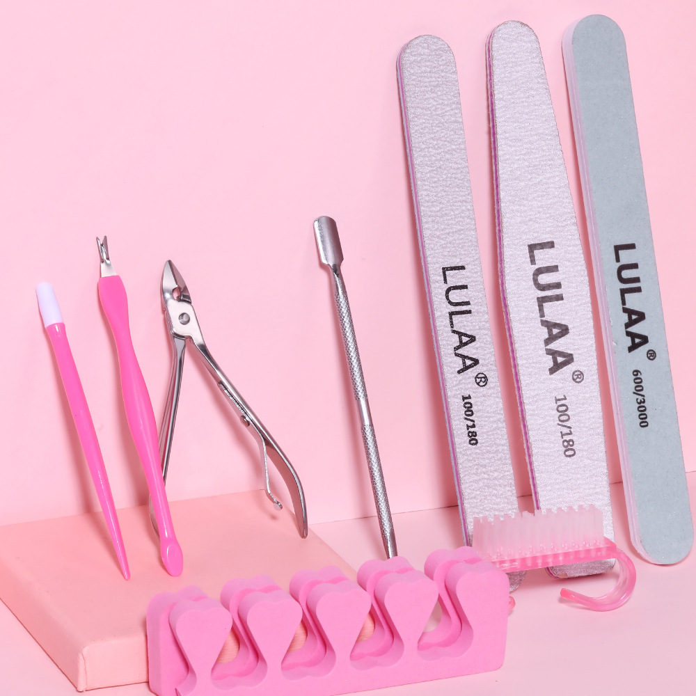 Manicure set featuring pink tools, including nail clippers, files, and a cuticle pusher on a pink background.