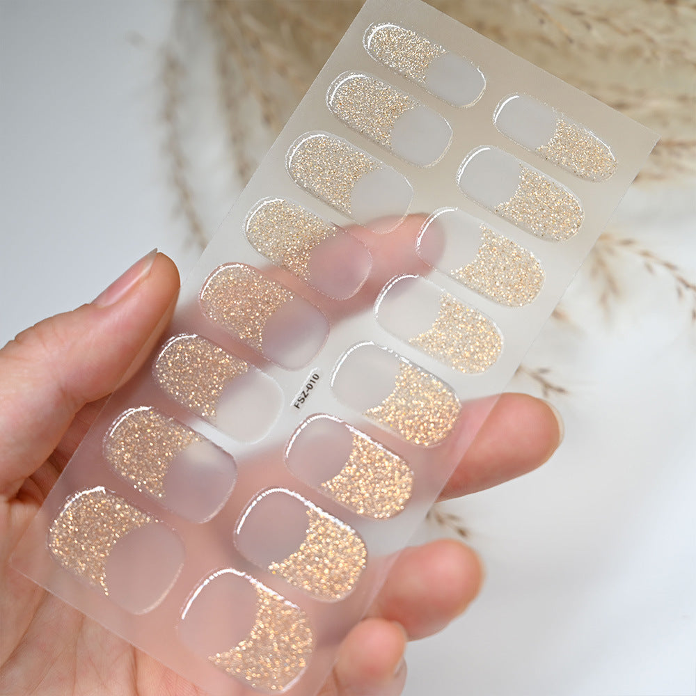 French Glitter nail wraps featuring a gold glitter design on a clear backing, held in a hand.