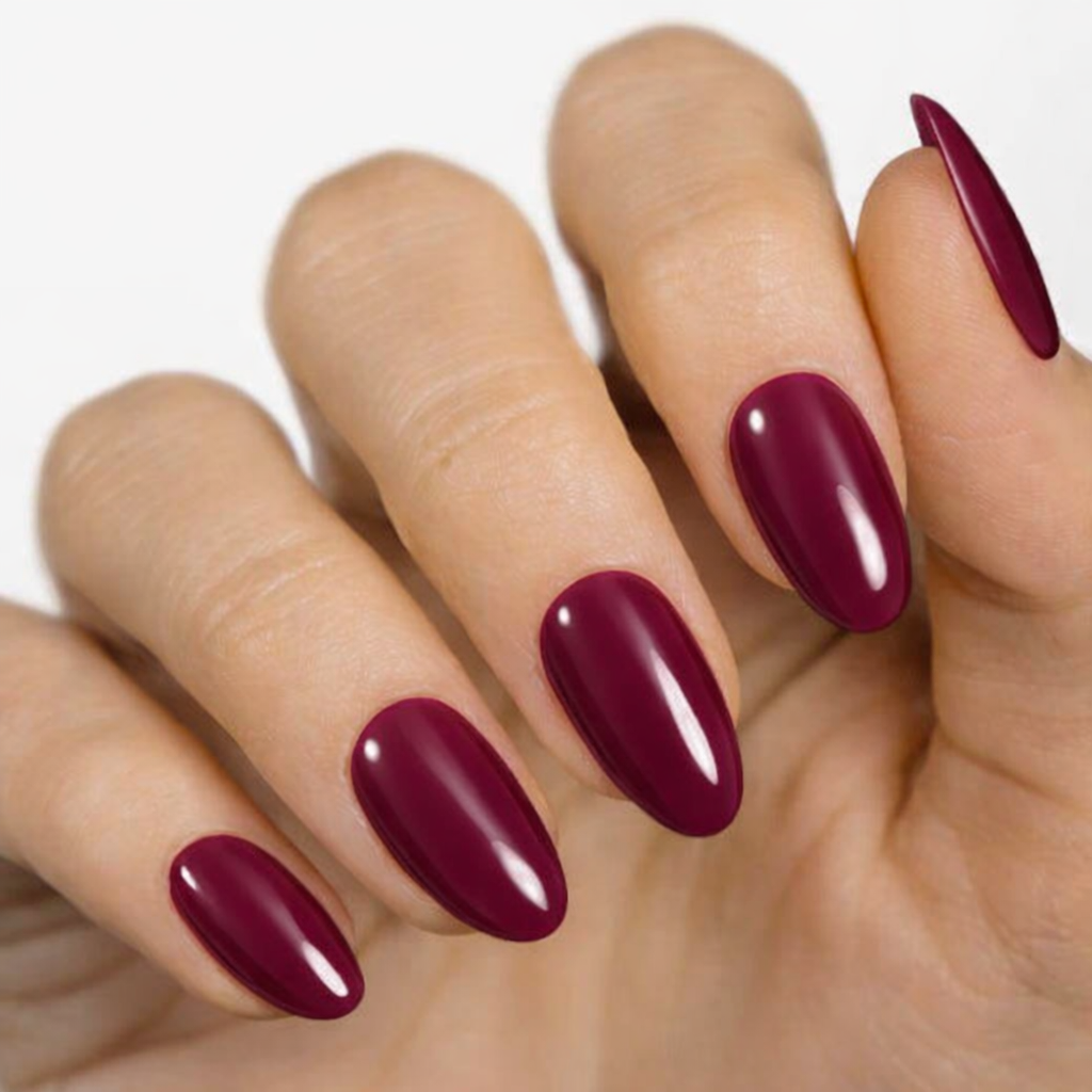 Currant™ nail wraps displayed on a hand with long, almond-shaped nails in a deep burgundy color.