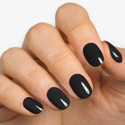 Jet black nail wraps applied on well-manicured fingers with a smooth finish.