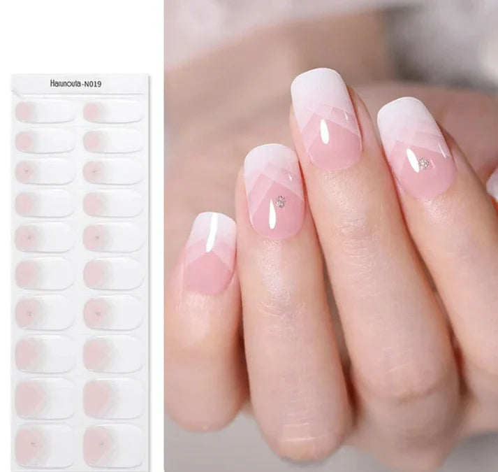 Delicate French press-on nails with a pink ombre design and silver accents on the tips, displayed on a hand.
