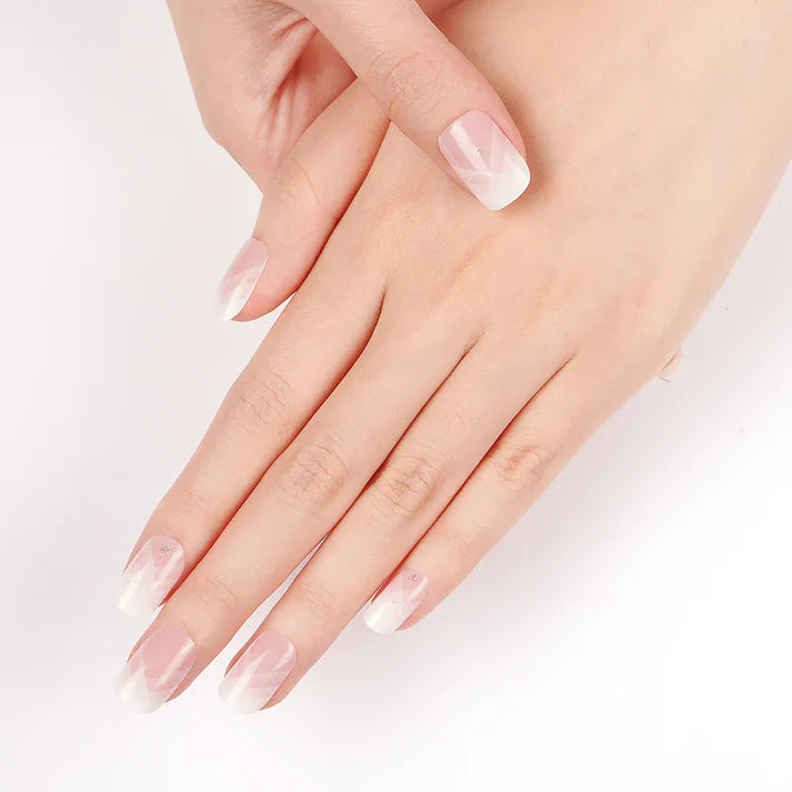 Delicate French manicure featuring soft pink and white tips on well-groomed hands against a white background.