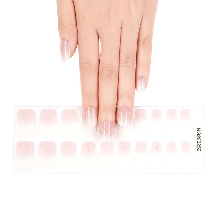 Delicate French press-on nails in a gradient design on a clear backing with a hand positioned above them.