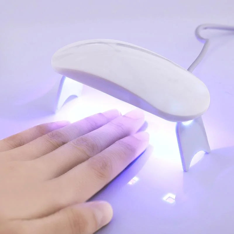 Currant UV lamp with a white marble design, illuminating a hand underneath for nail curing.