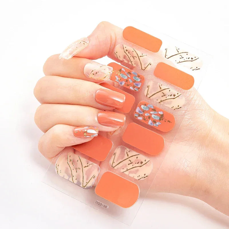 Currant™ nail wraps on a hand, showcasing floral patterns, orange accents, and a mix of nail shapes.