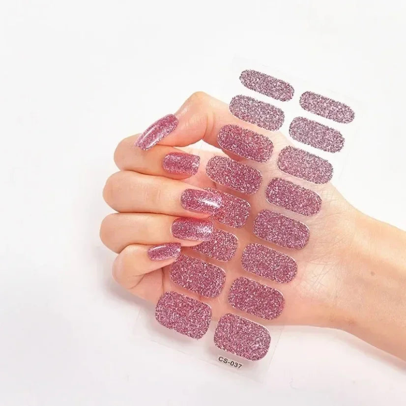 Currant™ Star nail wraps in a pink glitter design held by a hand with manicured nails.