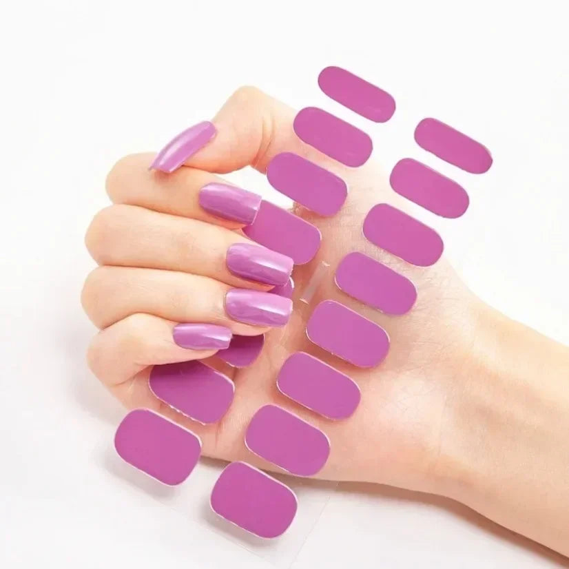 Long purple press-on nails on a hand, with matching adhesive purple nail wraps displayed beside them.