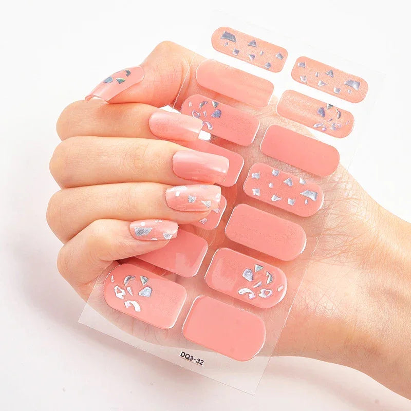 Currant™ nail wraps featuring pink nails with silver geometric designs on a clear backing, held in a hand.