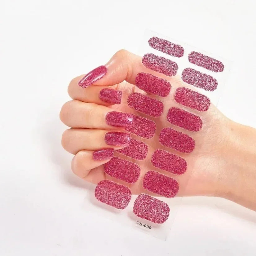 Currant™ Star nail wraps featuring a glittery pink design on a hand holding the sheet of wraps.