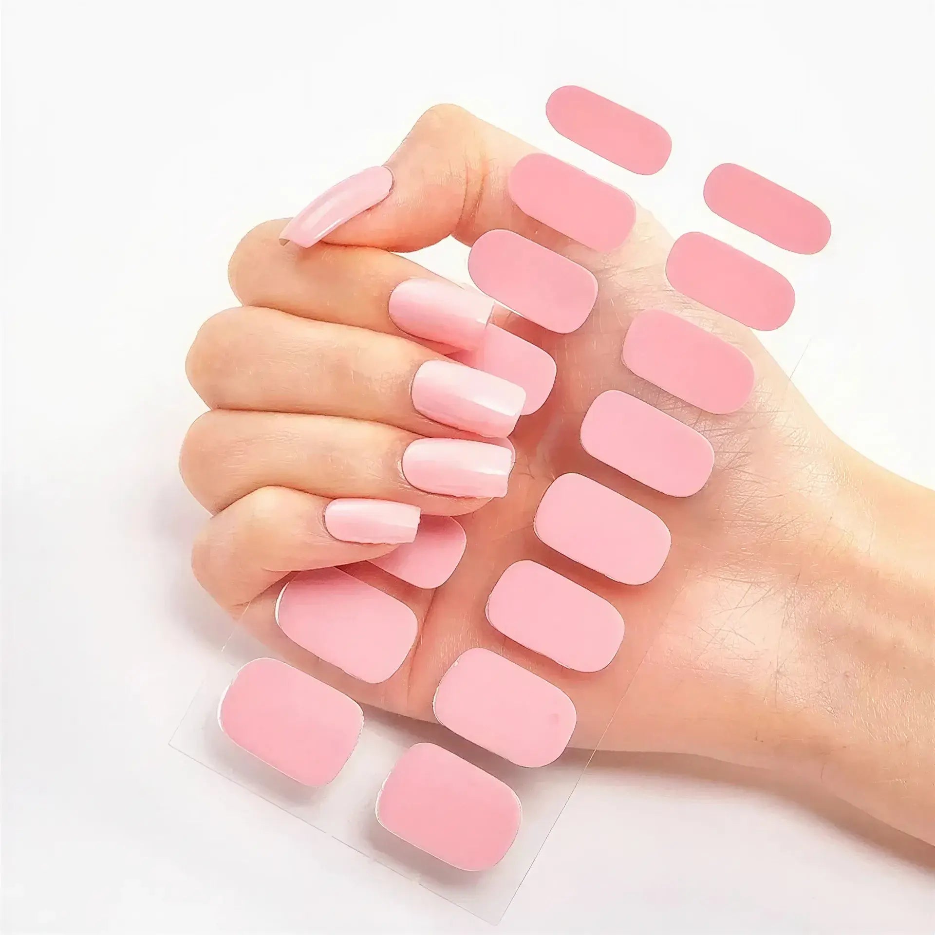 Currant™ nail wraps in a hand showing long pink nails alongside a sheet of matching pink nail wraps.