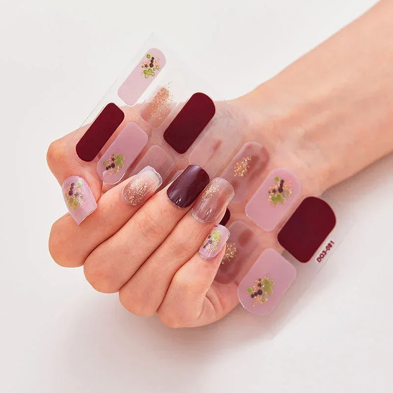Currant™ nail wraps featuring burgundy, pink, and glitter designs displayed on a hand with manicured nails.