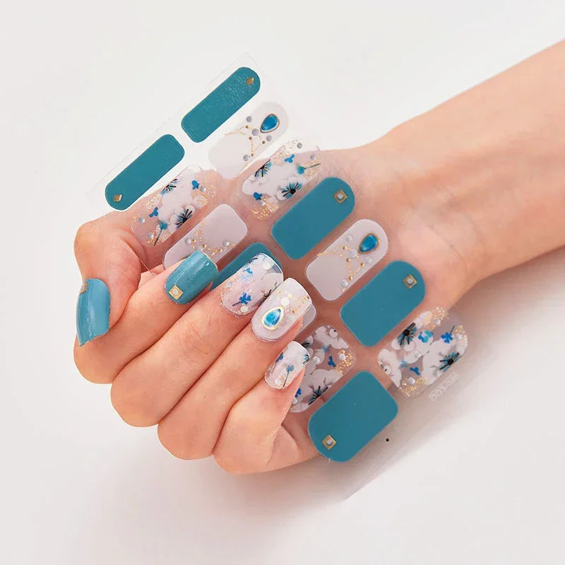 Currant™ nail wraps featuring teal and floral designs, arranged on a hand with manicured nails.