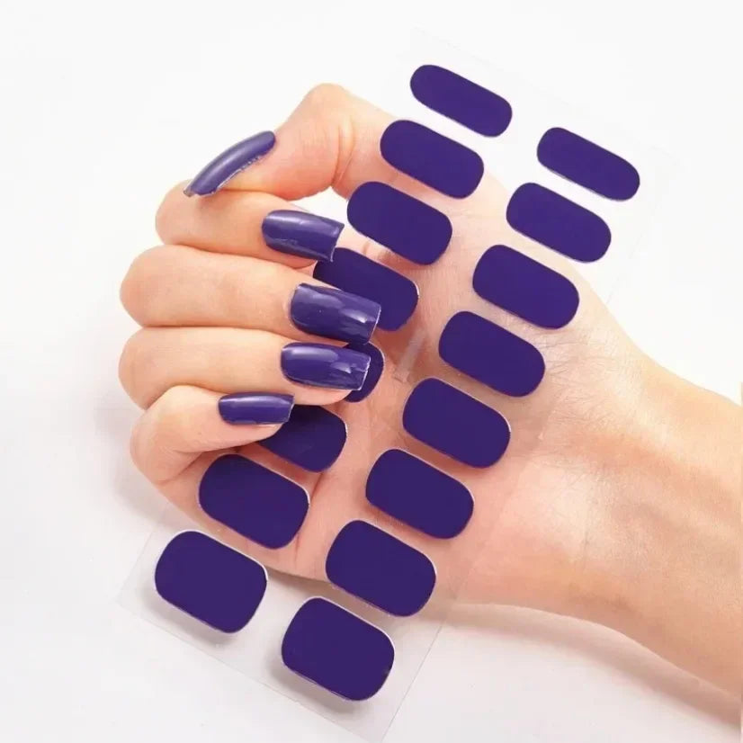 Currant™ nail wraps in various purple shades held by a hand with manicured nails on a white background.
