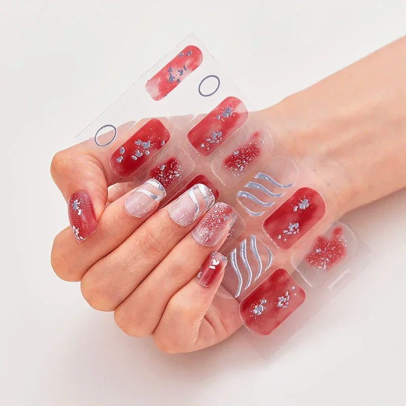 Currant™ press-on nails in red and clear with floral designs, silver accents, displayed on a hand.