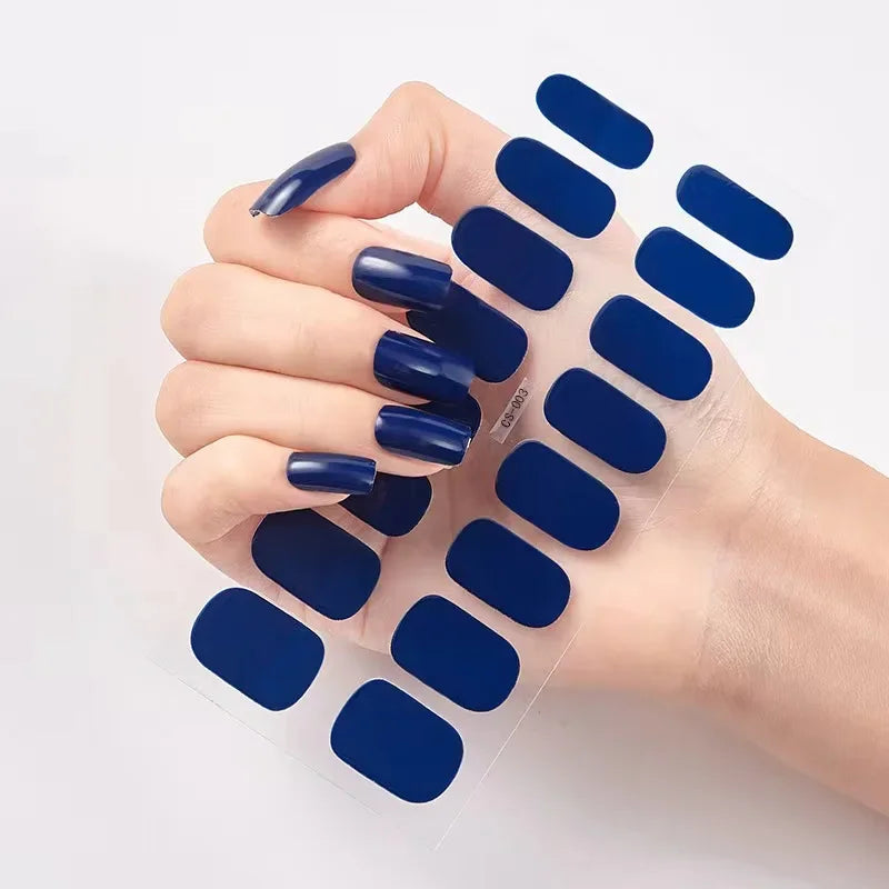 Currant™ nail wraps in navy blue held in a hand with long, polished nails, showcasing multiple designs.