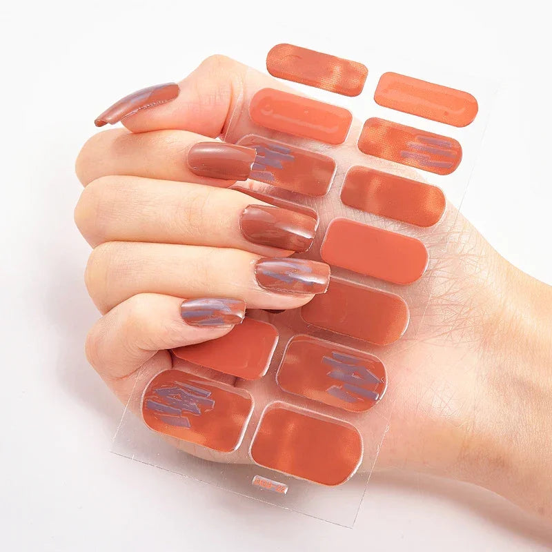Currant™ Star nail wraps shown on a hand with long, almond-shaped nails in a glossy brown and orange hue.