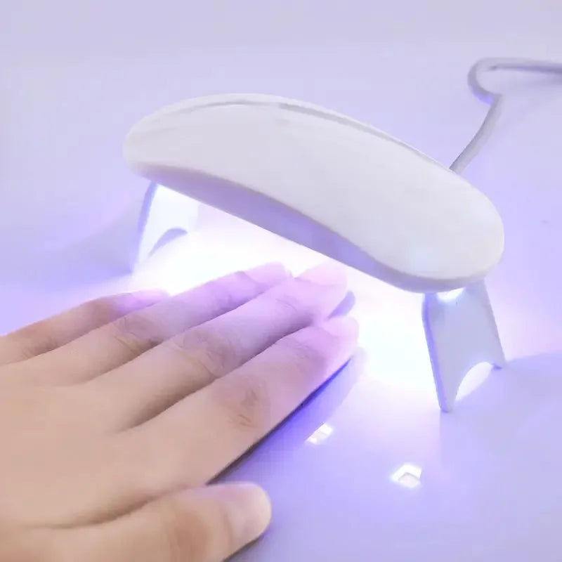 Currant UV lamp with a white curved design illuminating a hand underneath for nail curing.