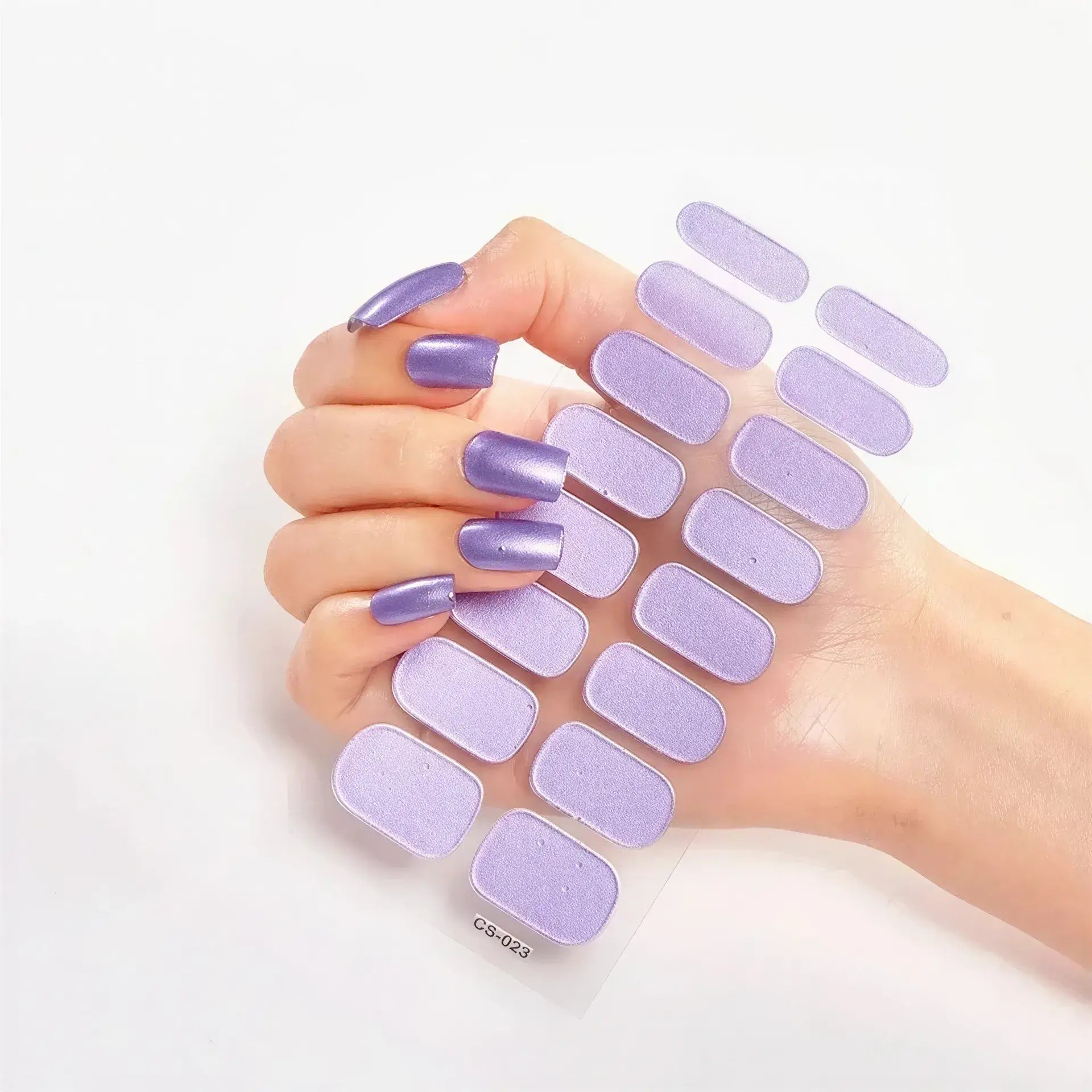 Currant™ nail wraps in various lavender shades held by a hand with long, glossy purple nails on a white background.
