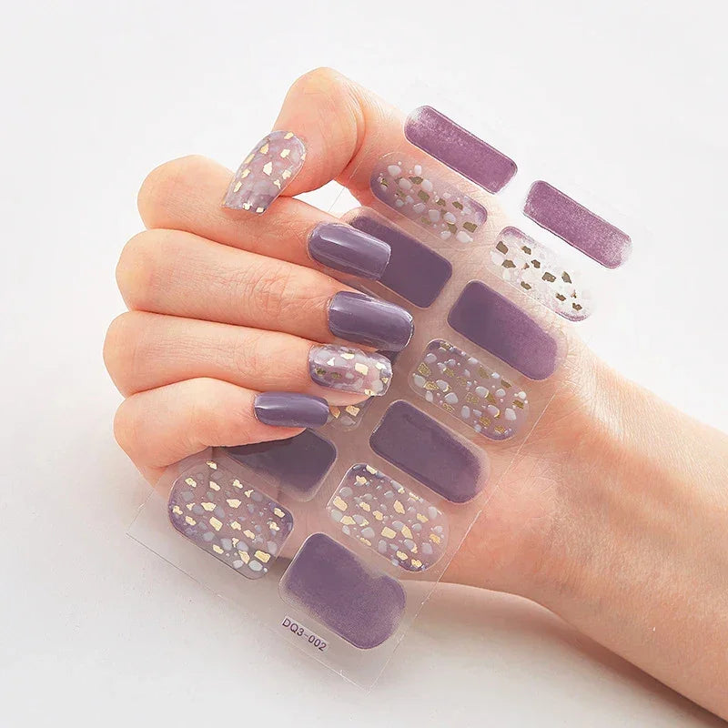 Currant™ Marble nail stickers featuring purple and gold designs on a clear backing, displayed on a hand with manicured nails.