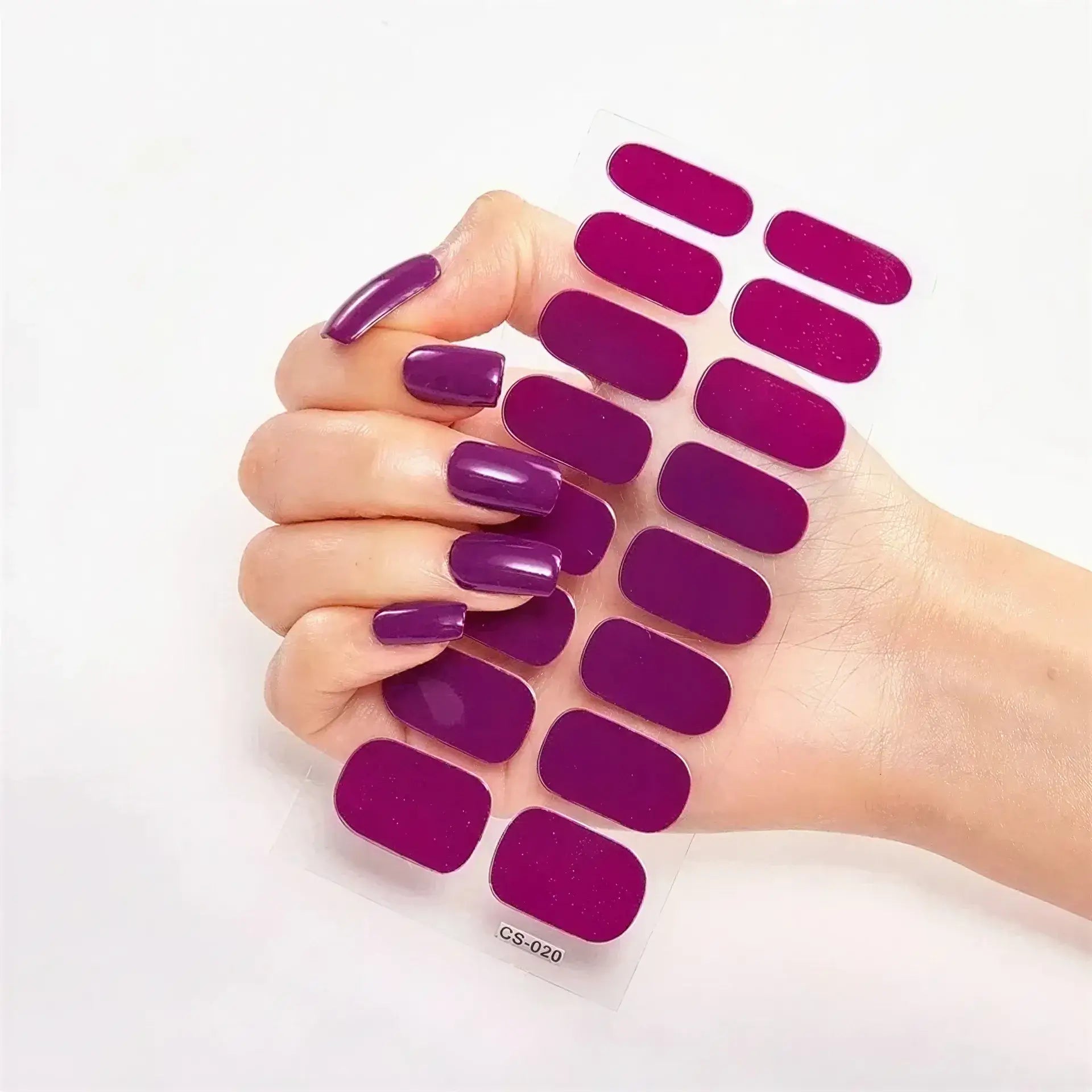 Currant™ nail wraps in glossy purple displayed on a hand with long, manicured nails holding a sheet of wraps.