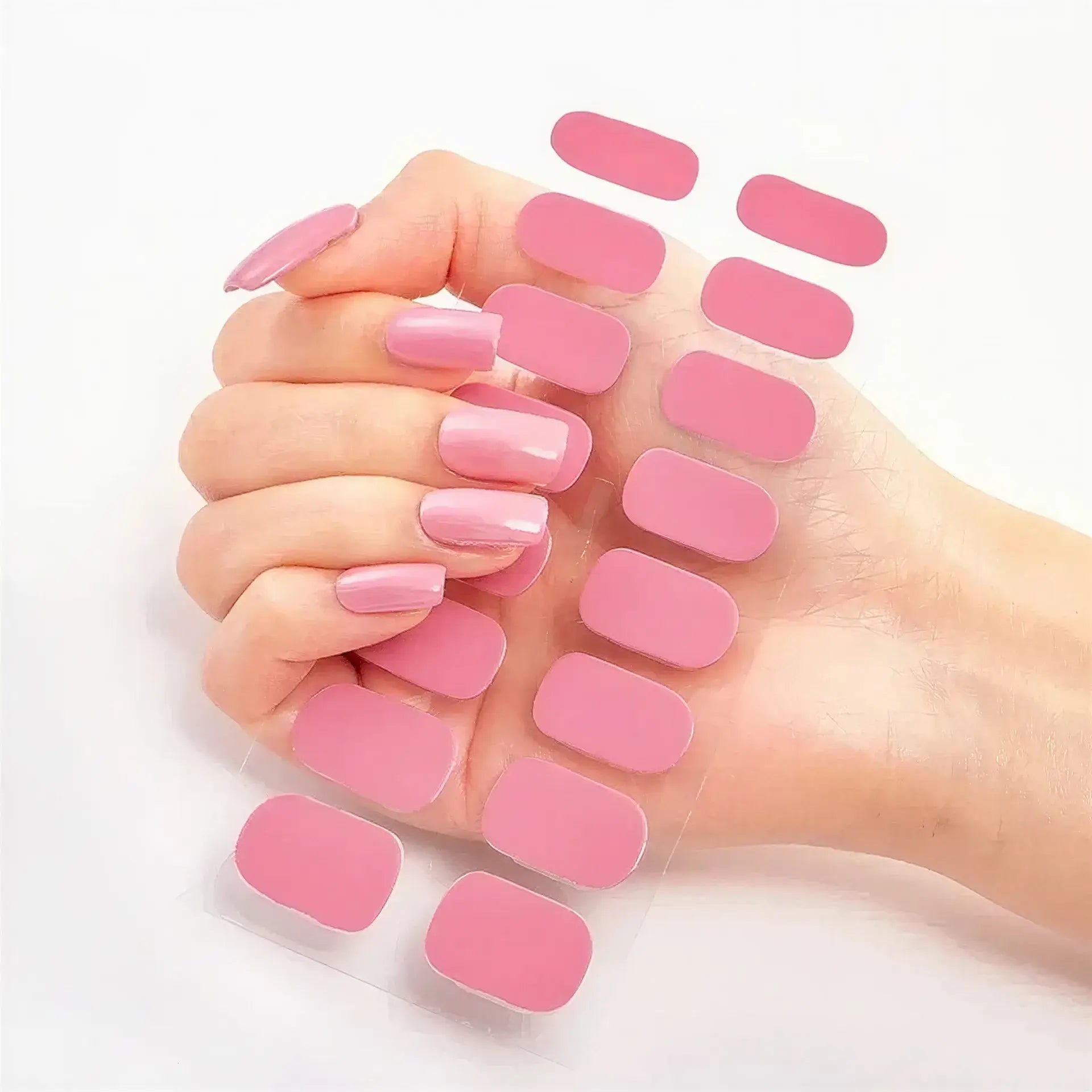 Currant™ nail wraps in a hand with manicured pink nails, holding a sheet of matching pink wraps.