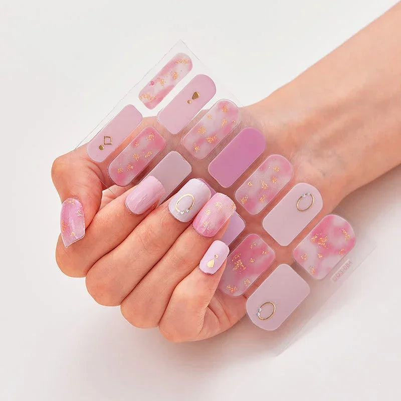 Currant™ press-on nails in pastel purple and pink with gold accents, displayed on a hand.