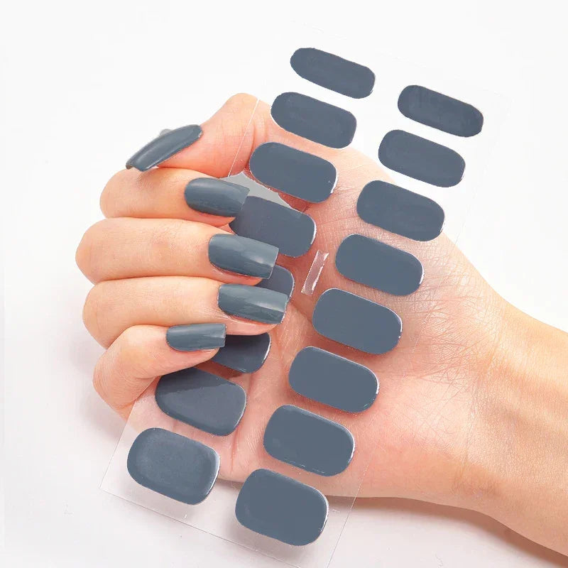 Currant™ nail wraps in gray held by a hand with long, manicured nails, showcasing the wrap sheet design.