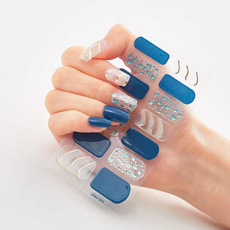 Currant™ Marble nail set featuring various blue shades, metallic accents, and decorative patterns on a clear backing.