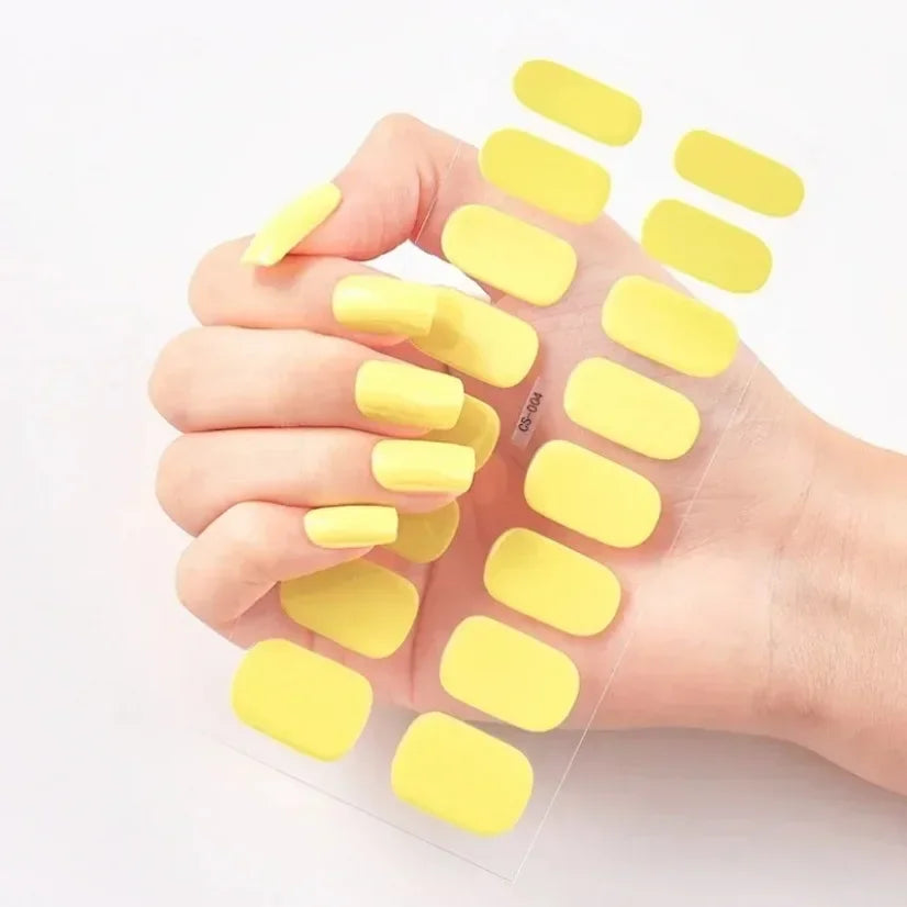 Currant™ nail wraps in yellow on a hand, showcasing various sizes and shapes on a clear backing.