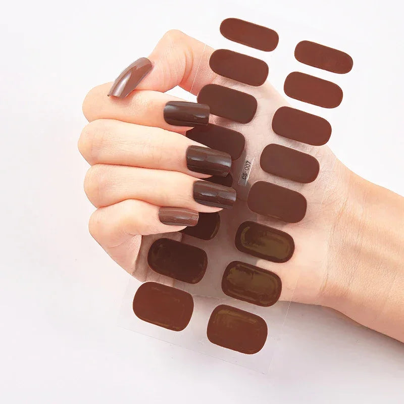 Currant™ nail wraps in dark brown displayed with a hand holding a sheet of matching nail strips.