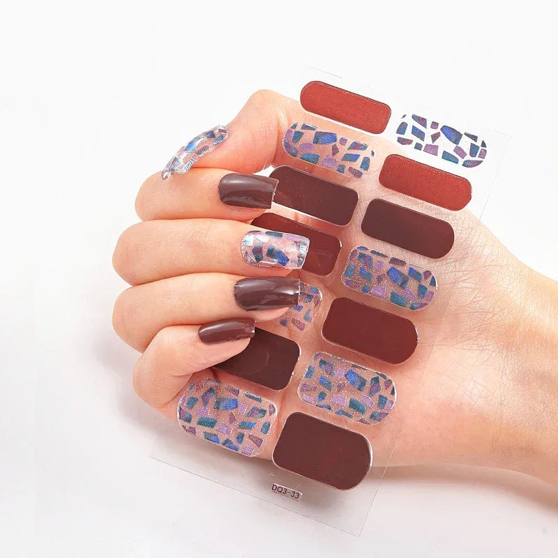 Currant™ nail wraps with red and patterned designs on a hand showing dark brown nails and a clear backing.
