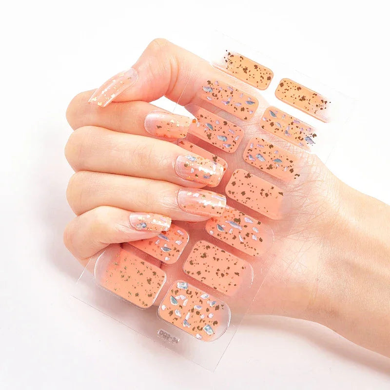 Currant™ fade peach nail wraps featuring gold and silver glitter accents, displayed on a hand with long nails.