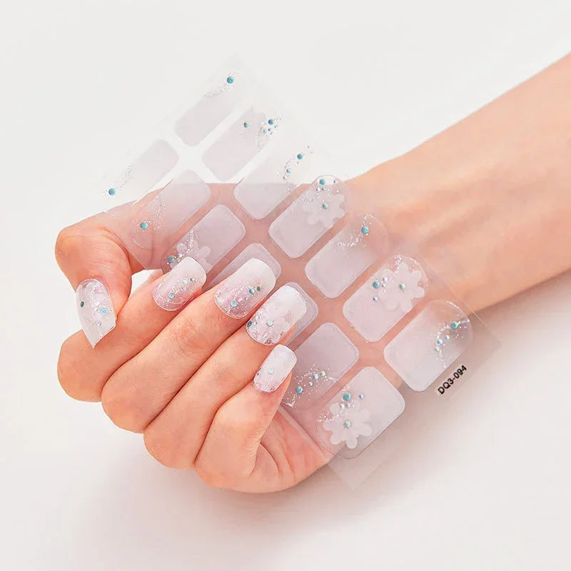 Currant™ Marble nail stickers with floral designs and blue embellishments on a hand with manicured nails.