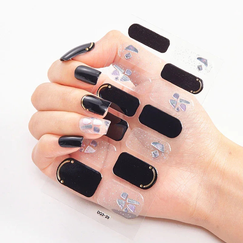 Currant™ nail wraps with black and clear designs, featuring decorative accents, displayed on a hand.