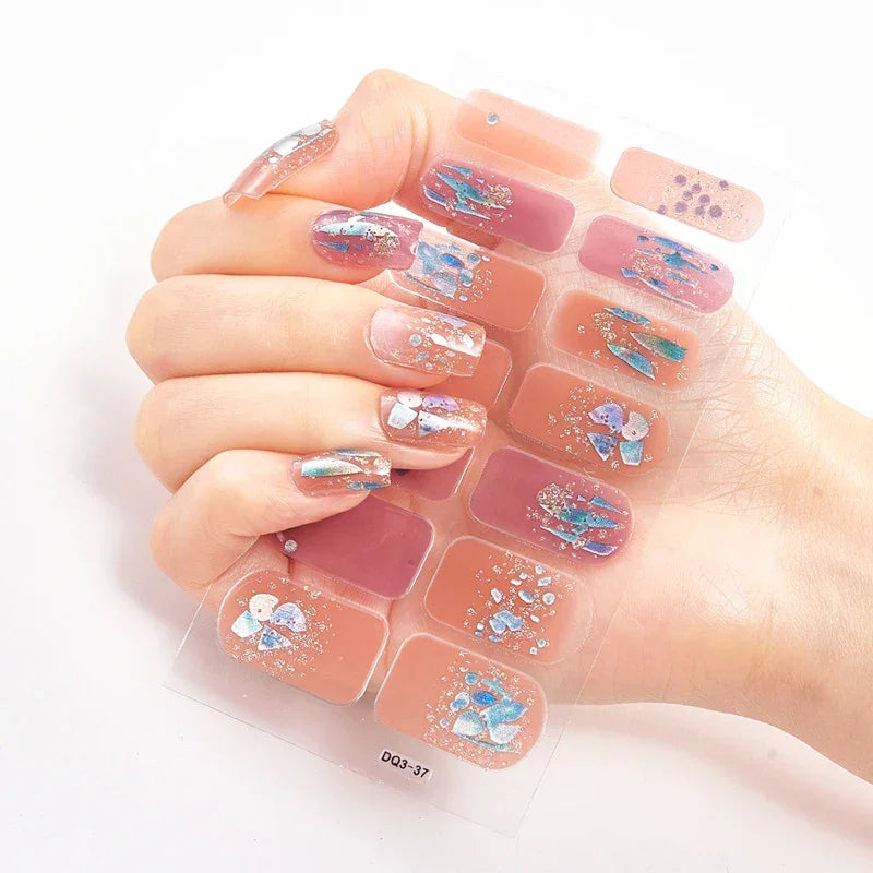 Currant™ press-on nails in pink and blue floral designs displayed on a hand holding a clear nail sheet.