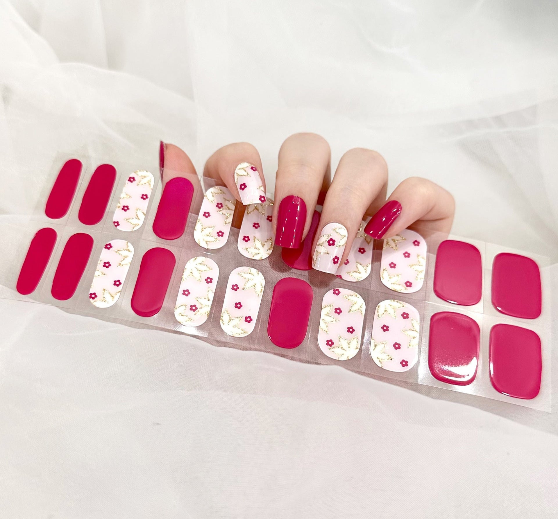 Currant™ Starter Kit with pink floral nail wraps, gold accents, and solid pink press-on nails on a clear backing.