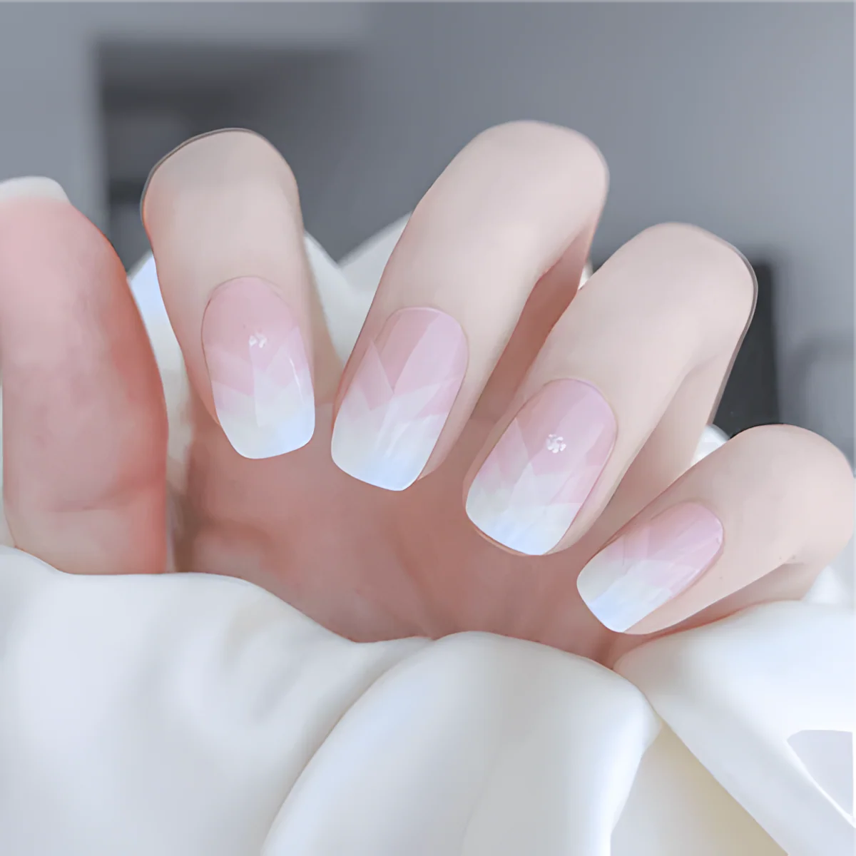 Delicate French manicure with a gradient of soft pink and white on long, square-shaped nails, set against a light background.